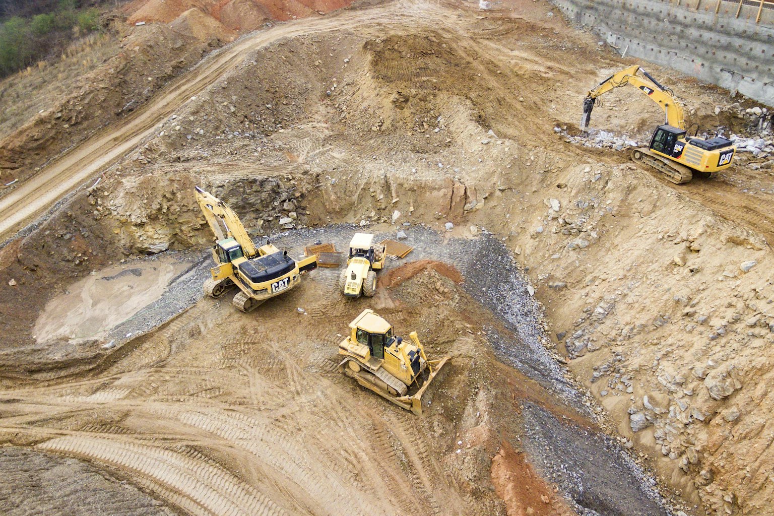 Aerial view of an earthworks site with excavators and machinery moving fill material